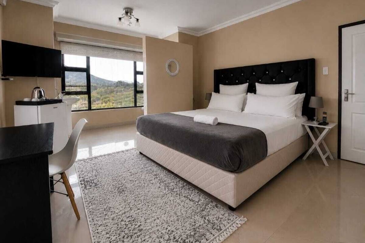 Un dormitorio con cama, escritorio, silla, televisor y ventana.