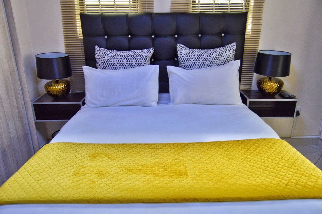 Quarto de hotel com uma cama grande, duas mesas de cabeceira e um painel de cabeceira.