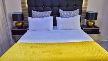 Quarto de hotel com uma cama grande, duas mesas de cabeceira e um painel de cabeceira.
