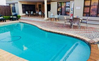 Una piscina con borde de azulejos, rodeada de mobiliario exterior y un patio cubierto.
