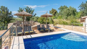 A swimming pool with lounge chairs and umbrellas, surrounded by stone walls and greenery. - Alcudia's Best: Private Pool, BBQ, Inviting Garden (Alcúdia)