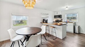 Cozinha moderna com área de refeições, um lustre e vista para o exterior.