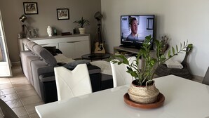 A modern living room with a dining area, a television, and a guitar. - Apartment beziers (Béziers)