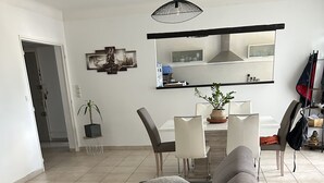 A modern living room with a grey sofa, a white rug, and a dining area with a table and chairs. - Apartment beziers (Béziers)