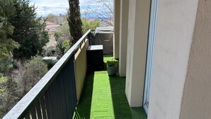 A balcony with artificial green turf, a potted plant, and a view of the sea. - Apartment beziers (Béziers)