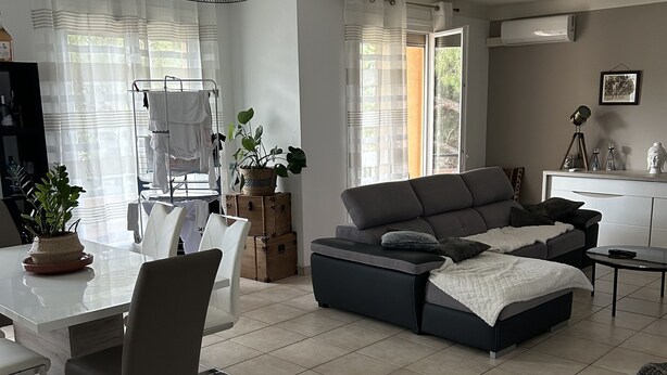 A modern living room with a grey sectional sofa, a dining table with chairs, and a kitchen area in the background. - Apartment beziers (Béziers)
