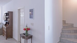 A hallway with a staircase, a wooden cabinet, and a small table with a vase of flowers. - Rethymno Heart Apartment (Rethymno)