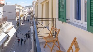 A narrow street with buildings on either side, a balcony with wooden chairs, and a clear blue sky. - Rethymno Heart Apartment (Rethymno)