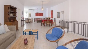 A living room with a sofa, coffee table, and chairs, a dining area with a table and chairs, and a staircase with a railing. - Rethymno Heart Apartment (Rethymno)