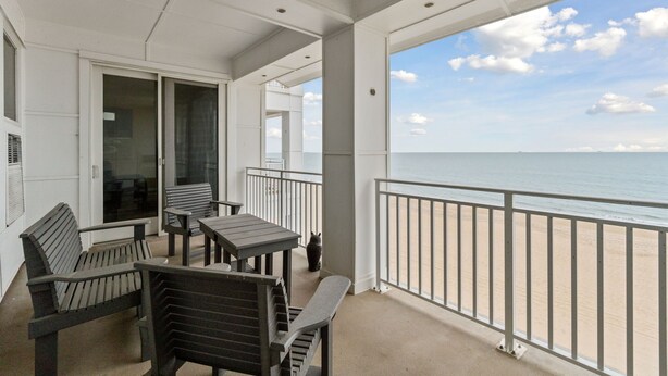 A balcony with a view of the beach, a table, and two chairs. - Book Mermaid's Lookout 410B | Sandbridge Oceanfront Rental (Virginia Beach)