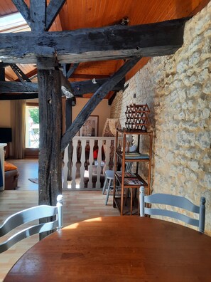 Ein rustikales Interieur mit freiliegenden Holzbalken, einer Steinwand und einem Holztisch mit Stühlen.