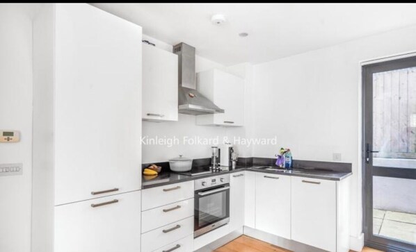 Enjoy cooking in this well-equipped kitchen with an oven, range hood, and black countertop.
