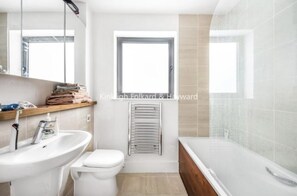 Enjoy a refreshing bath in the bathroom with a bathtub, glass-enclosed shower, and a large window offering a view of the outside.