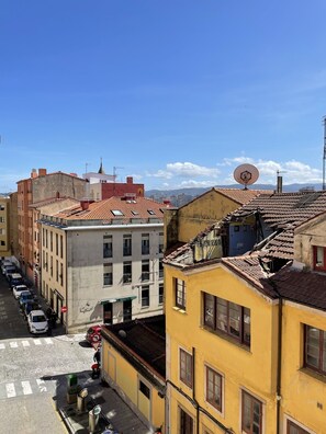 Une vue de rue avec des immeubles, des voitures garées et un ciel dégagé.
