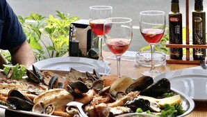 Un plateau de fruits de mer comprenant divers crustacés et poissons, accompagné de verres et de bouteilles de vin, le tout présenté sur fond de port de plaisance.