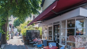 A cozy outdoor seating area with tables and chairs, a chalkboard menu, and a view of the street. - Bunny Cottage by Bloom Stays -  sleeps 4 guests  in 2 bedrooms (Saltwood)