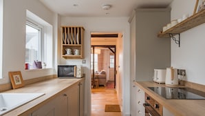 A kitchen with wooden countertops, a built-in microwave, and a shelf with kitchenware. - Bunny Cottage by Bloom Stays -  sleeps 4 guests  in 2 bedrooms (Saltwood)