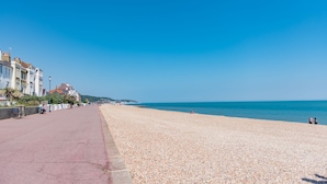 A pebbled beach with a paved walkway, buildings on one side, and the sea in the background. - Bunny Cottage by Bloom Stays -  sleeps 4 guests  in 2 bedrooms (Saltwood)