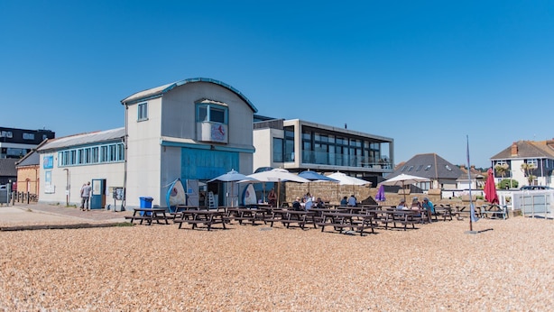 A beachside building with outdoor seating and umbrellas. - Bunny Cottage by Bloom Stays -  sleeps 4 guests  in 2 bedrooms (Saltwood)