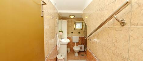 A bathroom with a toilet, sink, and shower area.