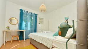 Une chambre à coucher comprenant un lit, un bureau, une chaise, une commode et un luminaire suspendu.