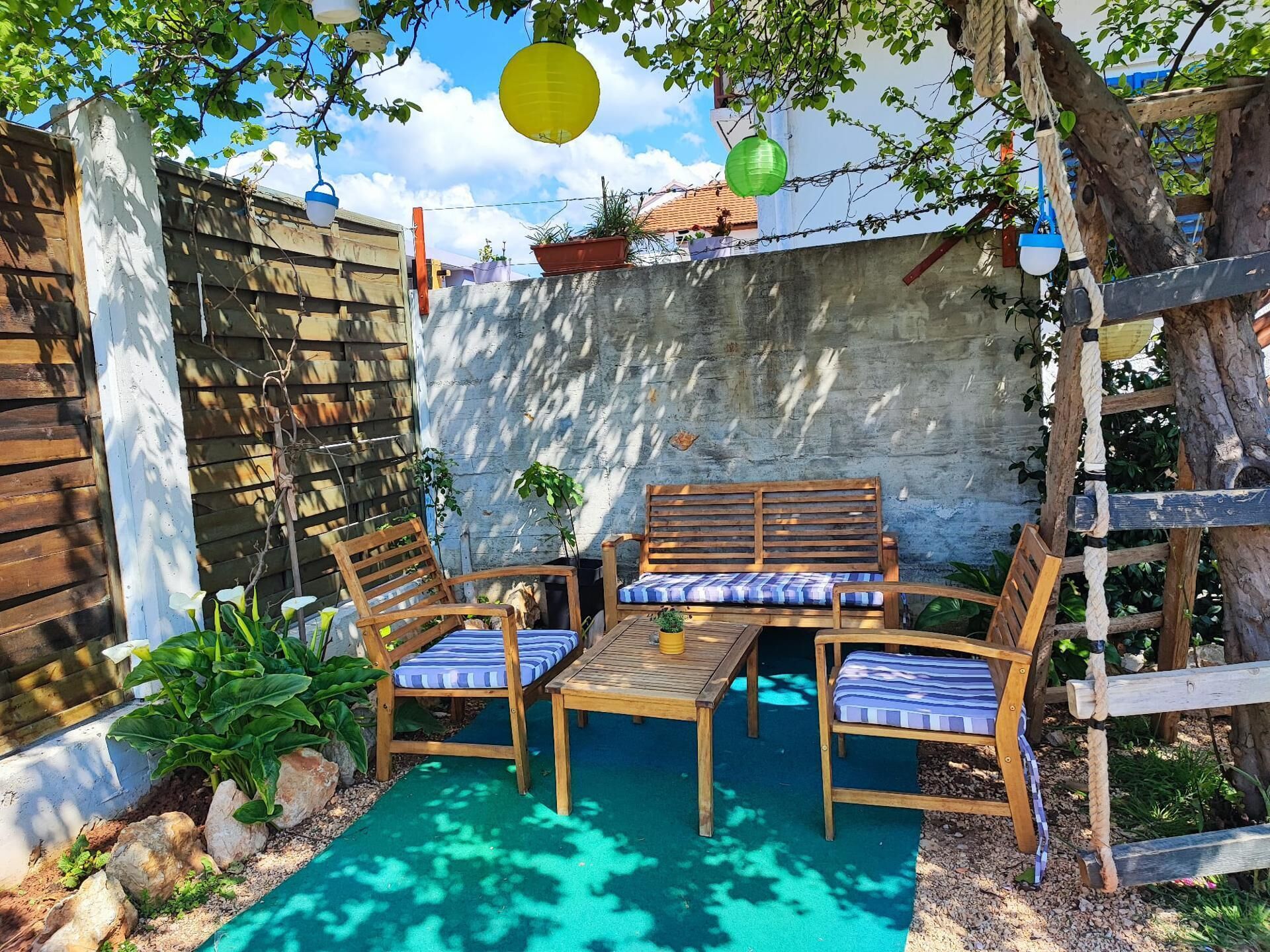 An outdoor seating area with wooden furniture and a concrete wall backdrop.