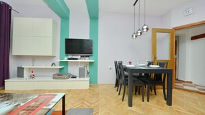 Un salon moderne doté d’un téléviseur à écran plat, d’une table à manger avec des chaises et d’un coin cuisine équipé d’un réfrigérateur et d’un four à micro-ondes.