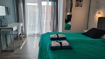 A hotel room with a bed, a desk, and a window with curtains.