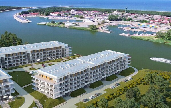 Een modern hotel met meerdere verdiepingen, een centrale binnenplaats en een jachthaven met boten.