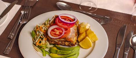 Un plato de comida con aguacate, tomate, cebolla y una ensalada sobre un plato blanco.