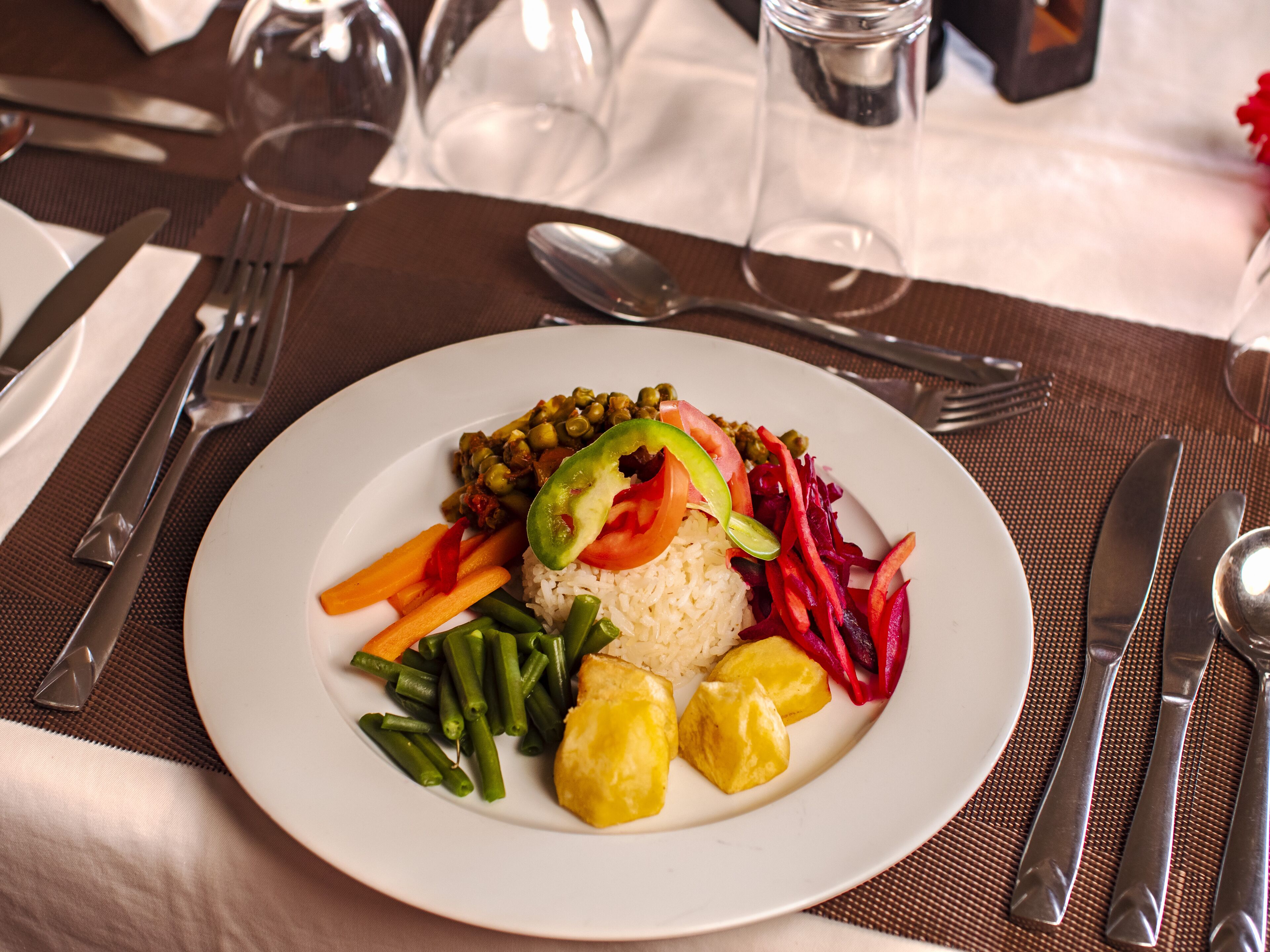 A plate of food with rice, green beans, carrots, tomatoes, beets, and potatoes.