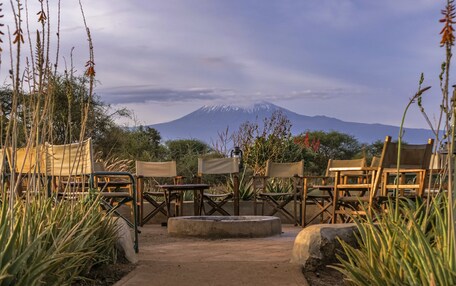 A seating area with chairs and tables, a concrete path, and a view of a mountain.