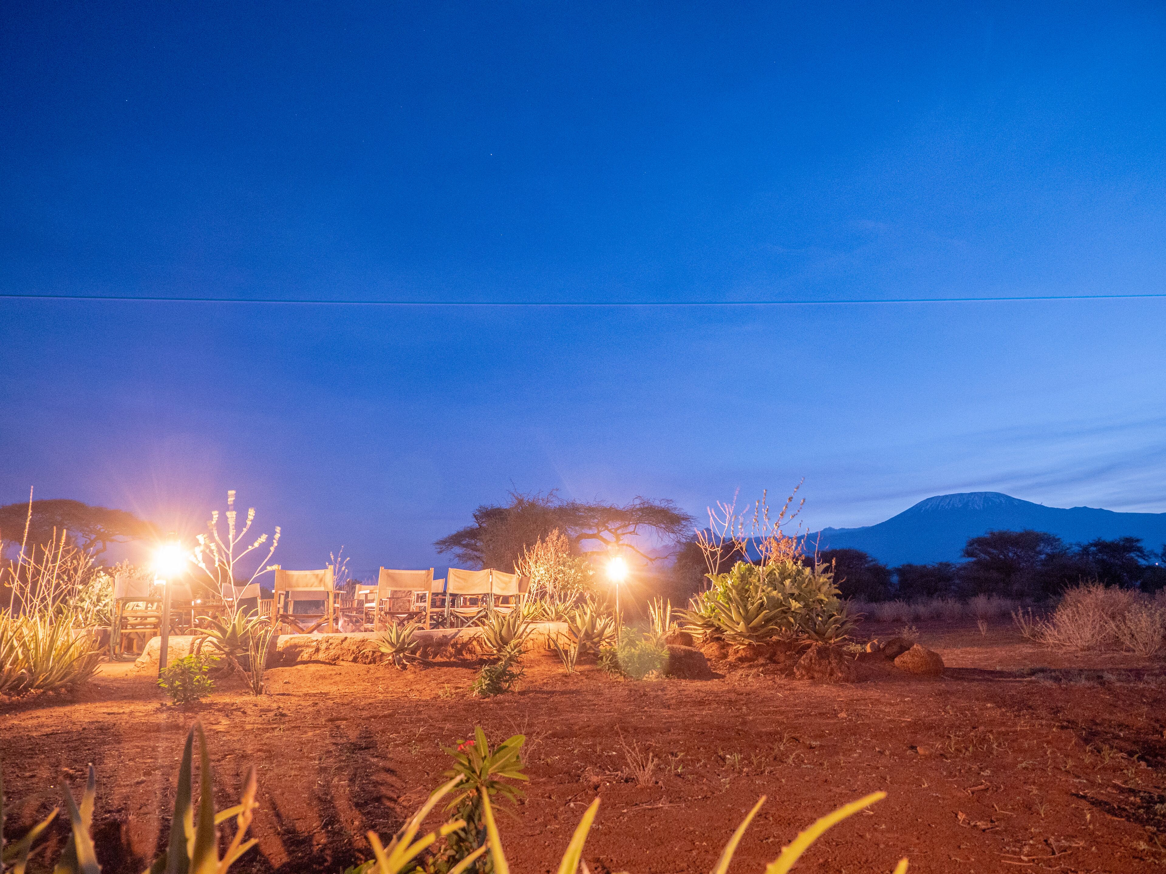A desert landscape at dusk with a building in the background.