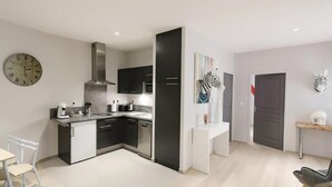A modern kitchen with black cabinets, a stainless steel range hood, and a white countertop. - Le Porta 5 (Albi)