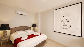 A hotel room with a bed, two bedside lamps, an air conditioner, and a large abstract painting on the wall.
