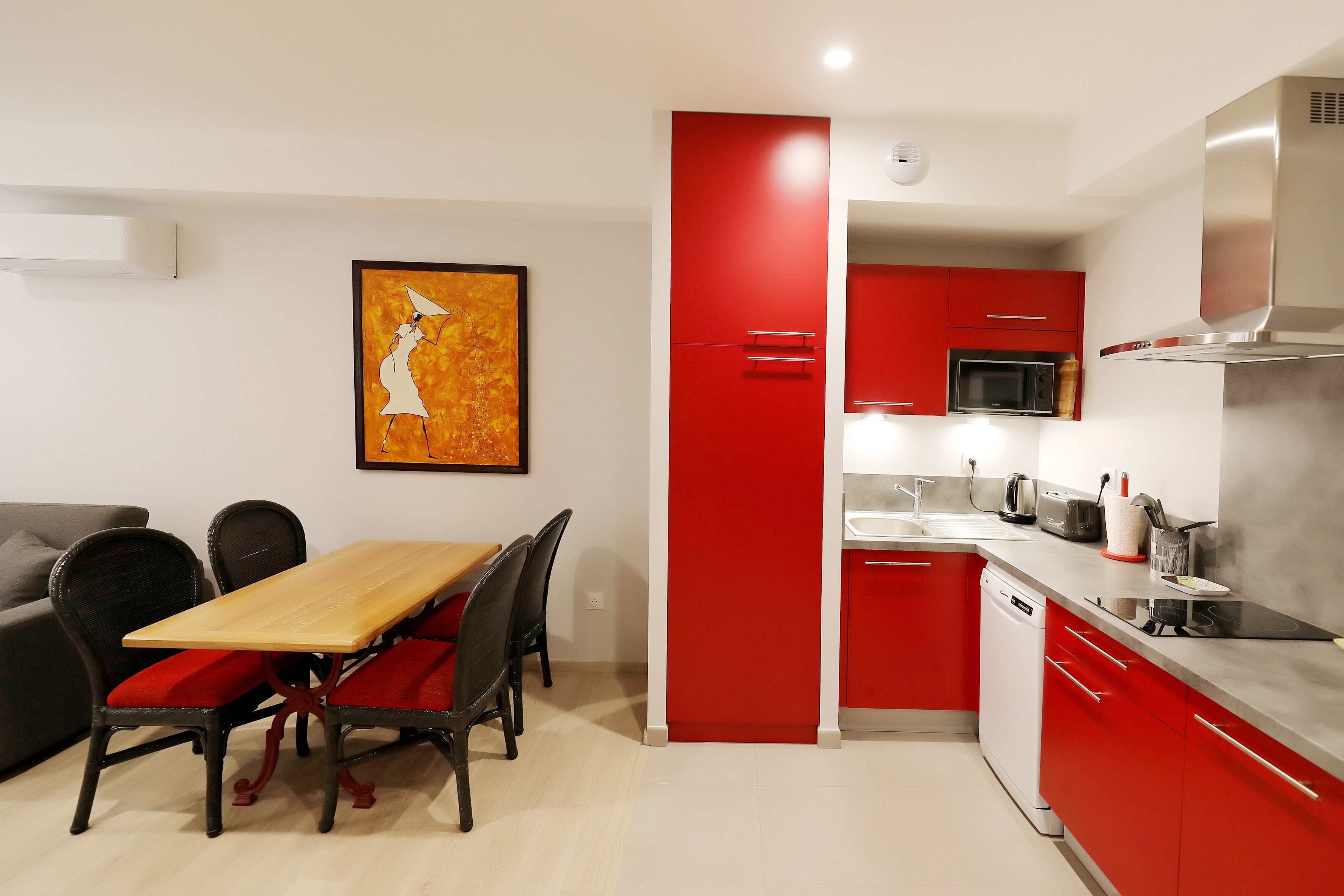 Una cocina moderna con armarios rojos, una mesa de comedor de madera y un microondas negro.