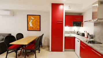 Una cocina moderna con armarios rojos, una mesa de comedor de madera y un microondas negro.