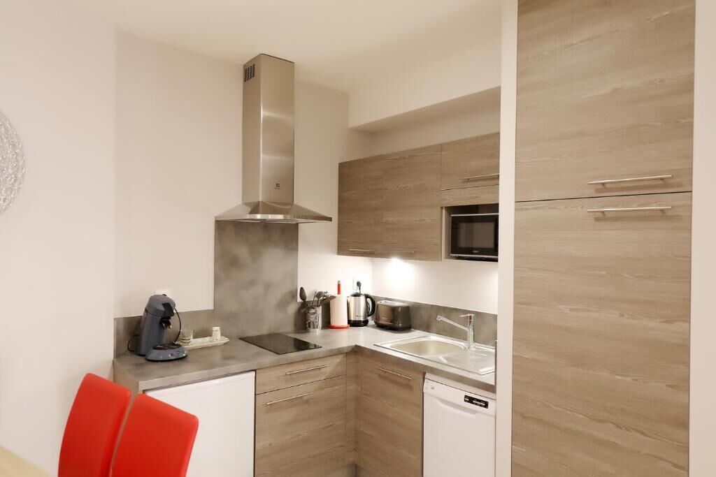 A modern kitchen with a microwave, stove, and dishwasher. There are wooden cabinets and a stainless steel range hood.