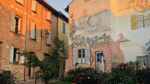 A courtyard with a brick wall, a mural, and a garden with flowers. - Le Porta 5 (Albi)