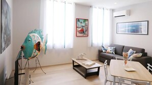 A modern living room with a sofa, a dining table, and a large fish sculpture. - Le Porta 5 (Albi)