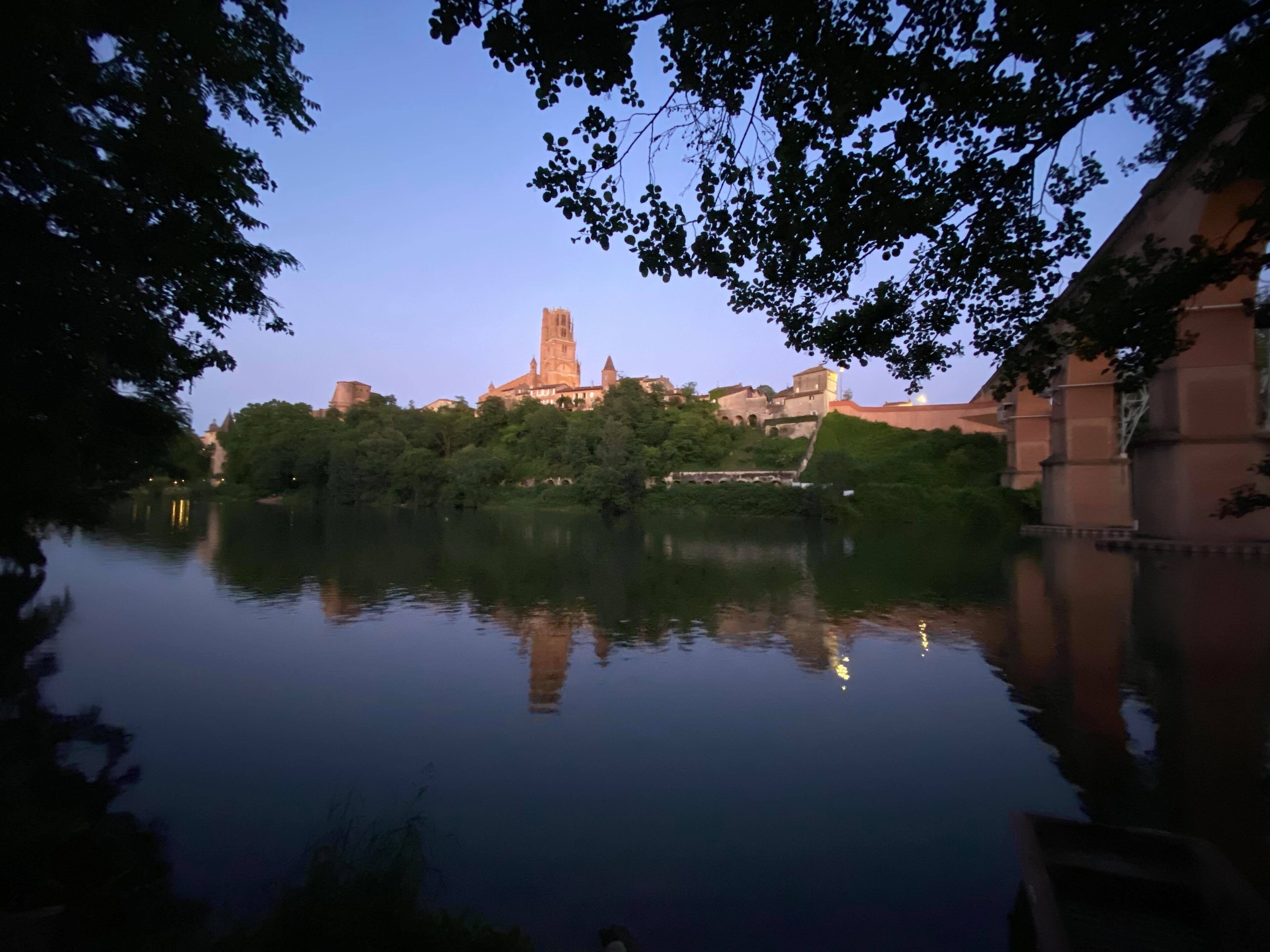 A tranquil riverside view with a historic tower and lush greenery.