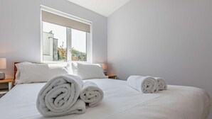 Une chambre d’hôtel avec un grand lit, deux oreillers blancs et deux serviettes blanches roulées.