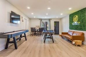 Un salon moderne avec une table de billard, un canapé et une table de jeu de billard.