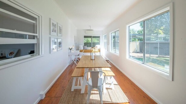 A long, narrow room with a wooden table and chairs, large windows, and white walls. - Cobbora Cottage -  Sleek & Stylish, Near Hospital (Dubbo)