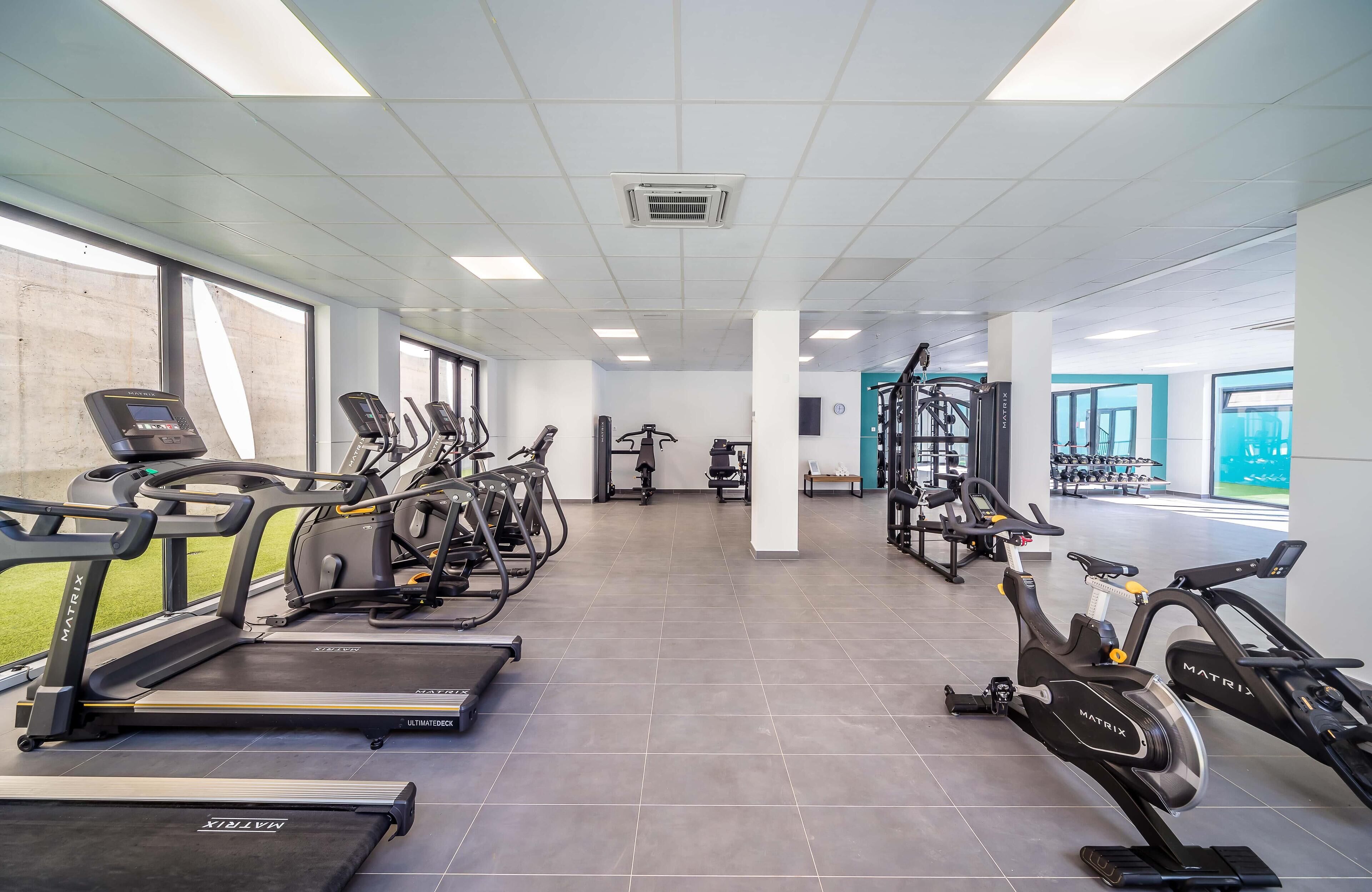 Ein Fitnessstudio mit Laufbändern, Crosstrainern und Gewichtsmaschinen.
