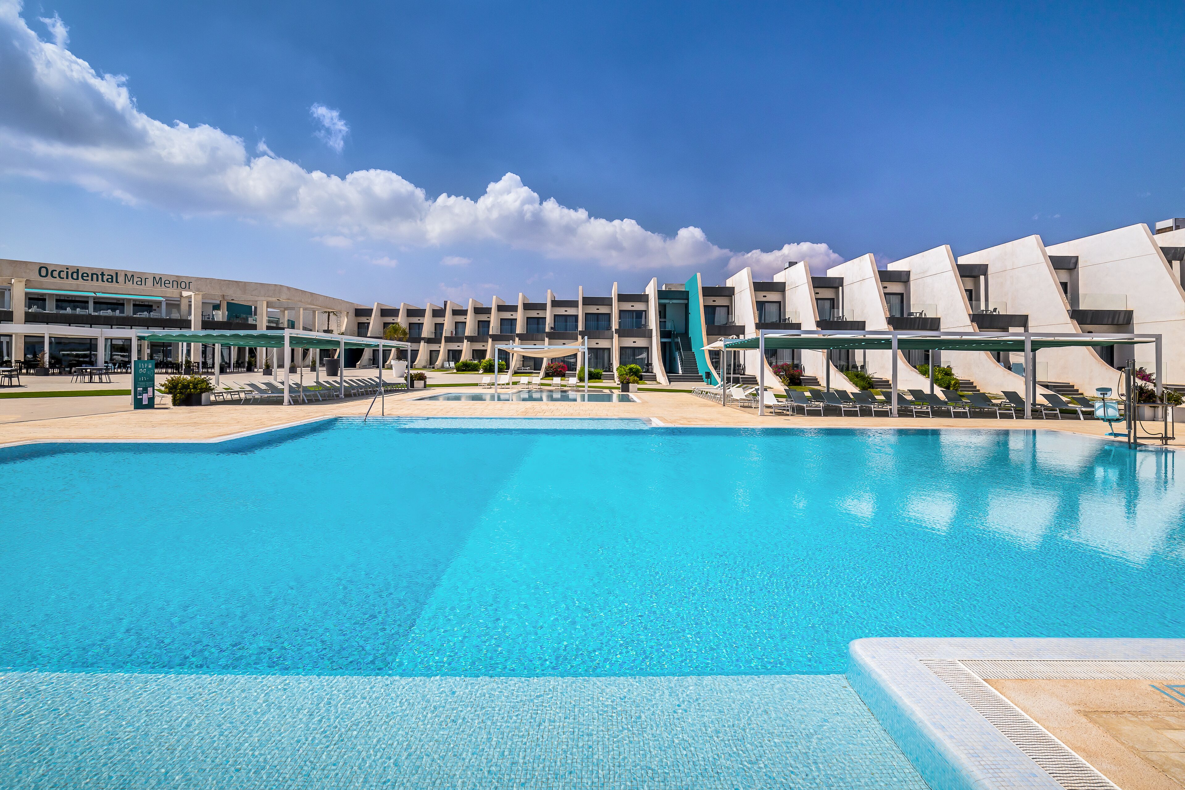 A swimming pool with lounge chairs and a building labeled "Occidental Mar Menor" in the background.