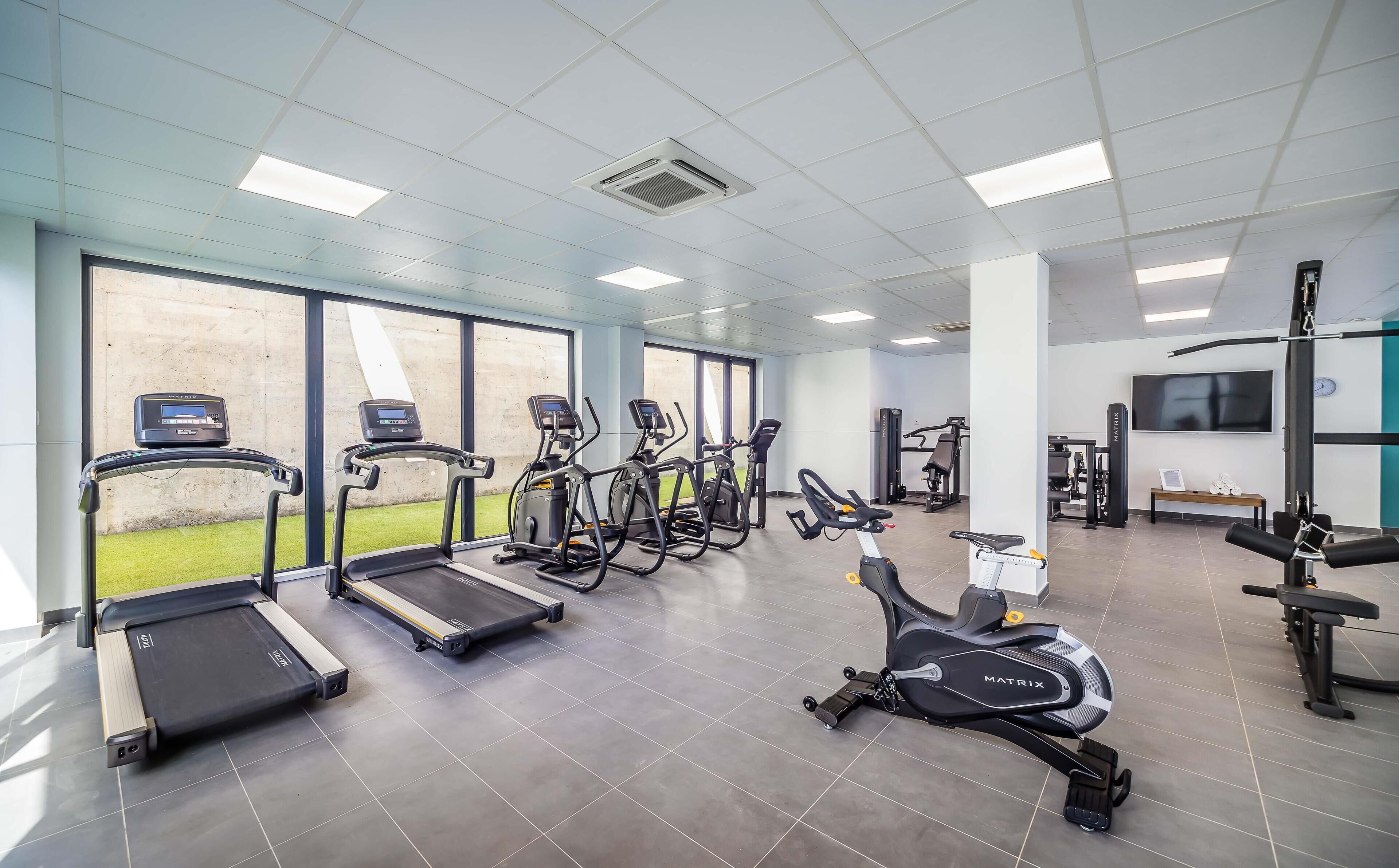 Une salle de sport équipée de tapis de course, de vélos elliptiques et d’appareils de musculation.