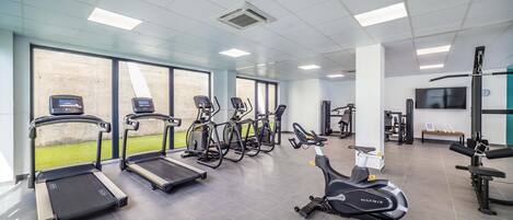 Une salle de sport équipée de tapis de course, de vélos elliptiques et d’appareils de musculation.