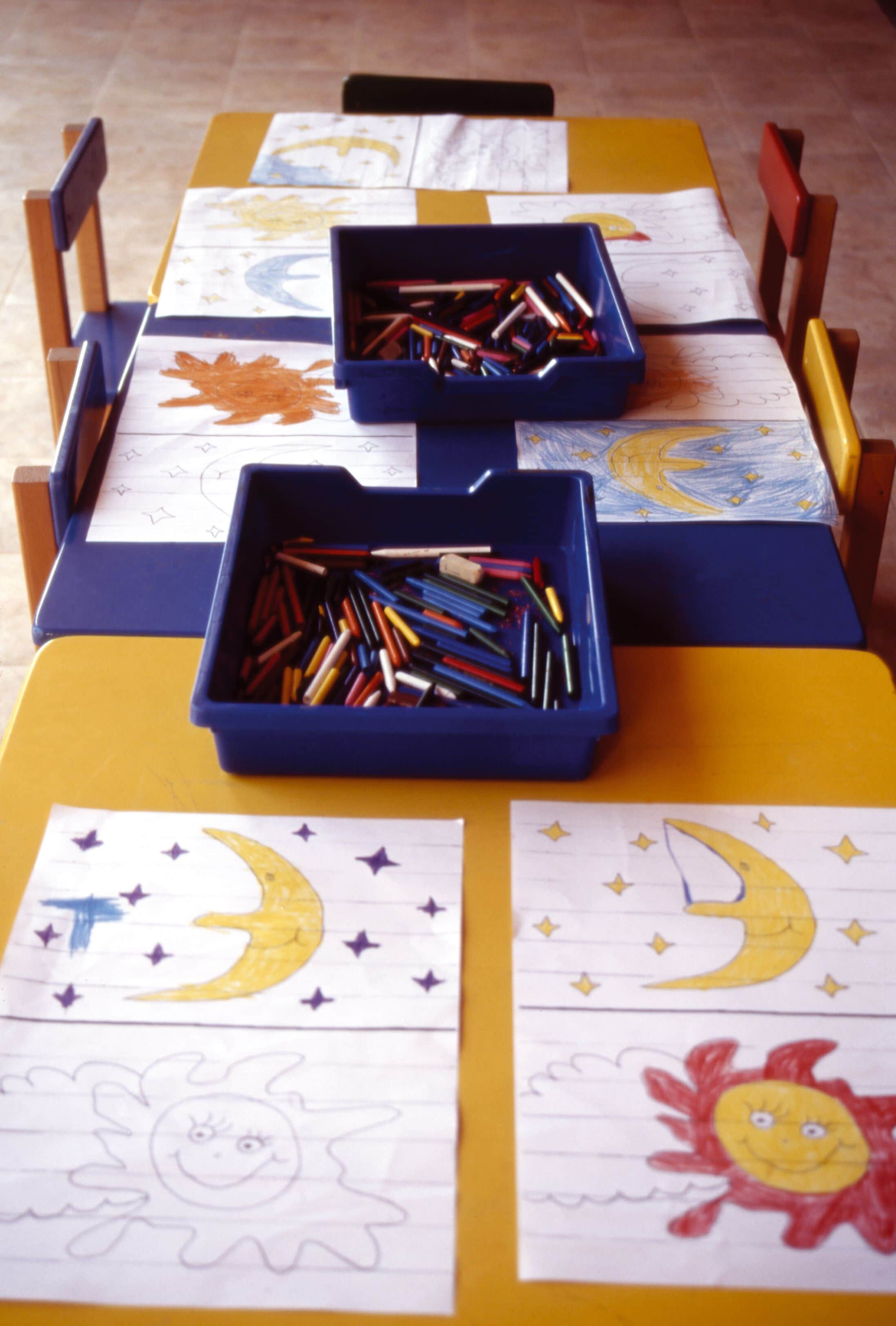 Una mesa con dibujos infantiles y lápices de colores.