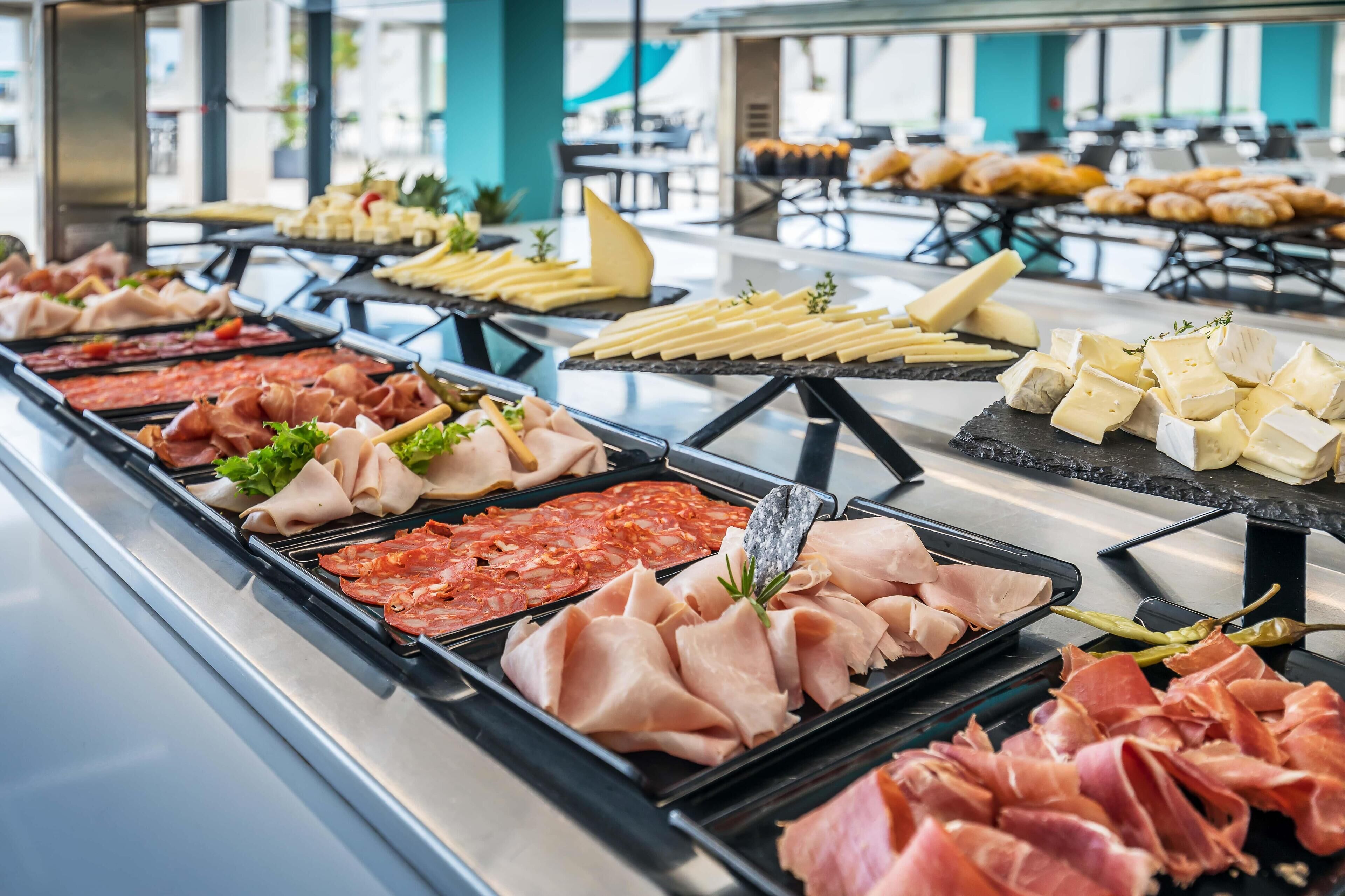 A buffet with various meats and cheeses.